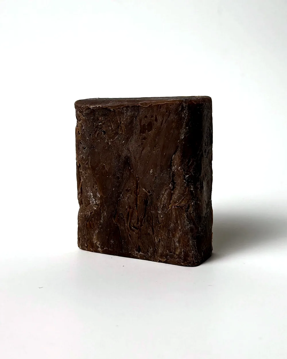 The bar unwrapped, dark brown with a rustic, textured face